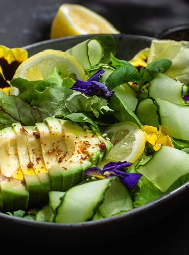 Salade avec avocats, tranches de citrons et fleurs comestibles